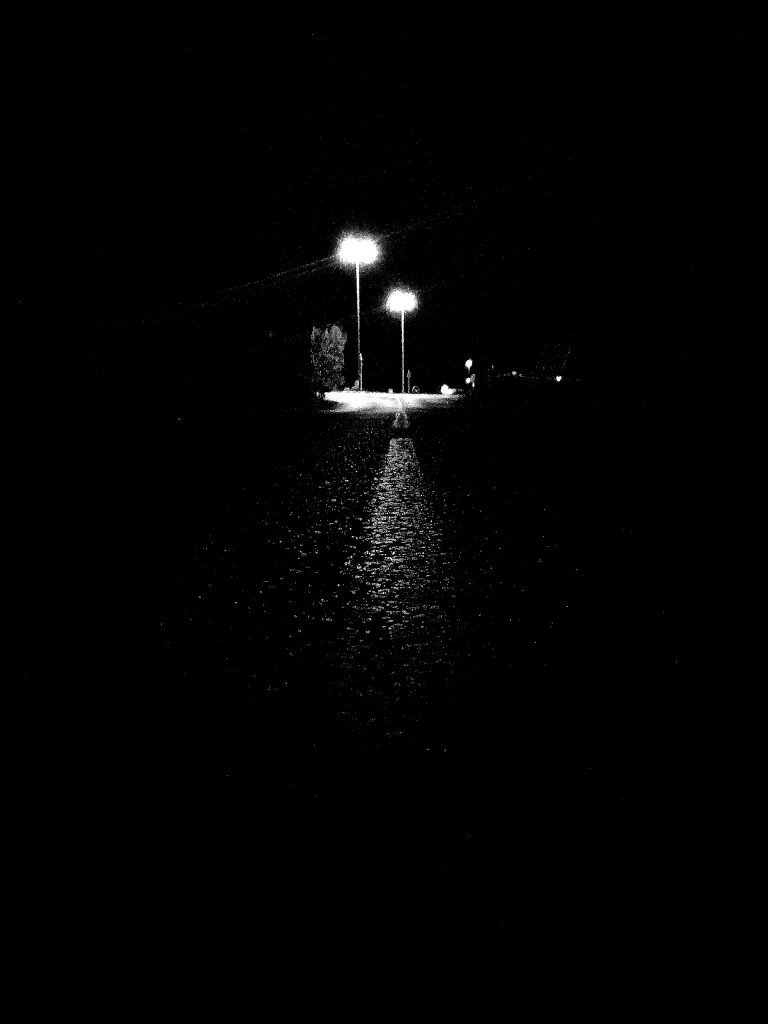 Photo prise de nuit où l'on peut voir uniquement un carrefour éclairé par 2 lampadaires au loin